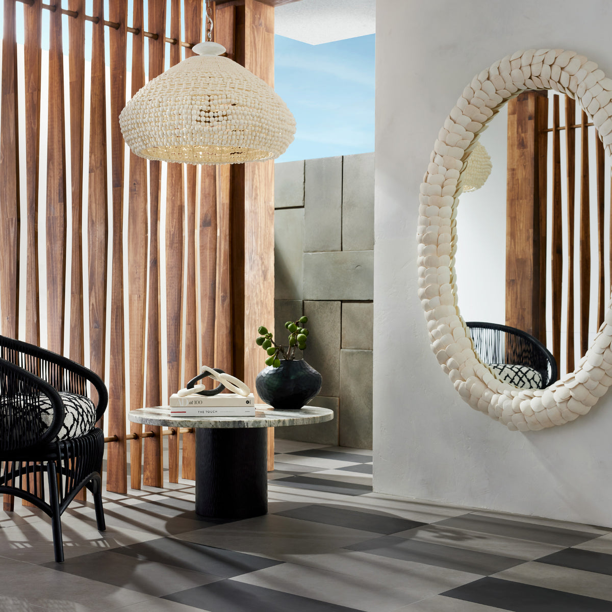 White coconut shell oval mirror in a sunlit room with a woven chair