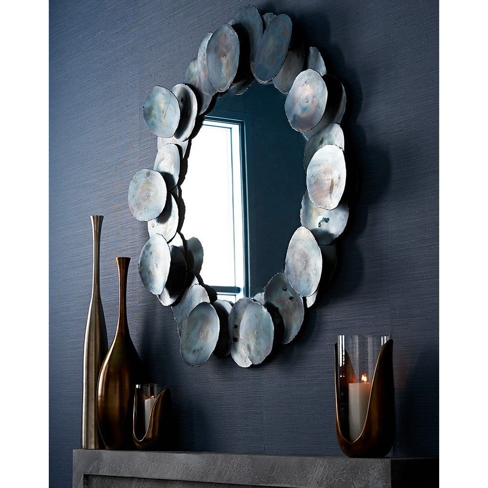 Oxidized iron disc mirror above a console on a navy wall