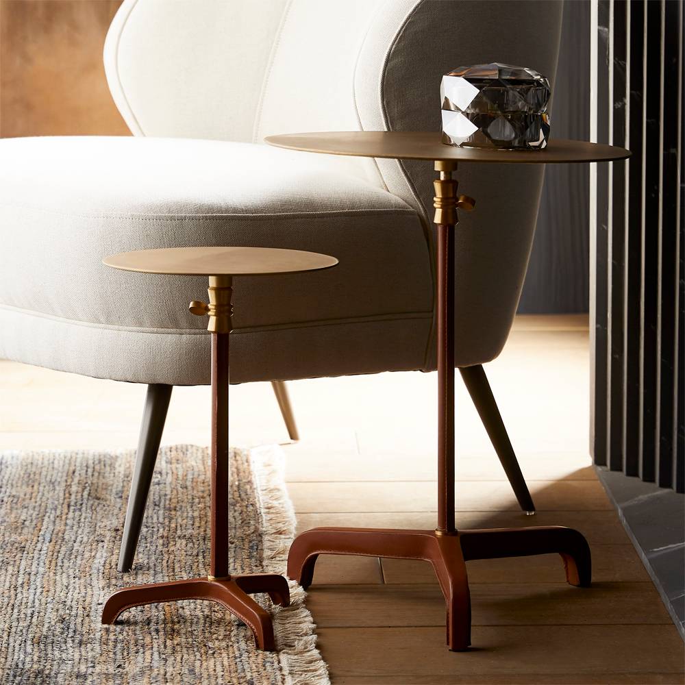 Leather-wrapped brass drink tables beside a cream lounge chair